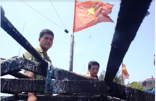 Thuyền trưởng Bùi Văn Phải và ngư dân Phạm Quang Thạnh bên con tàu cháy. Ảnh: LÊ VĂN CHƯƠNG 