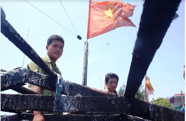 Thuyền trưởng Bùi Văn Phải và ngư dân Phạm Quang Thạnh bên con tàu cháy. Ảnh: LÊ VĂN CHƯƠNG 