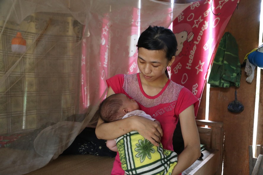 Chị Phùng A Tranh (vợ anh Xồng Bá Xò) bế đứa con hơn 1 tháng tuổi trên tay vui mừng khi đã được trở về quê