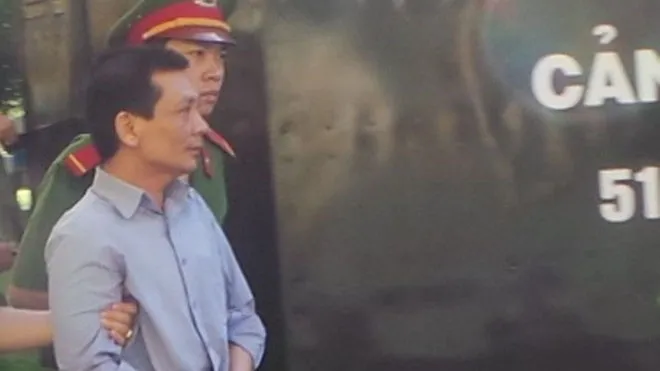 Tiến bị dẫn giải sau phiên tòa. 