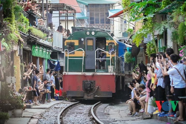 Du khách bất chấp nguy hiểm chụp ảnh tàu chạy qua khu cà phê đường tàu Ảnh: VOV