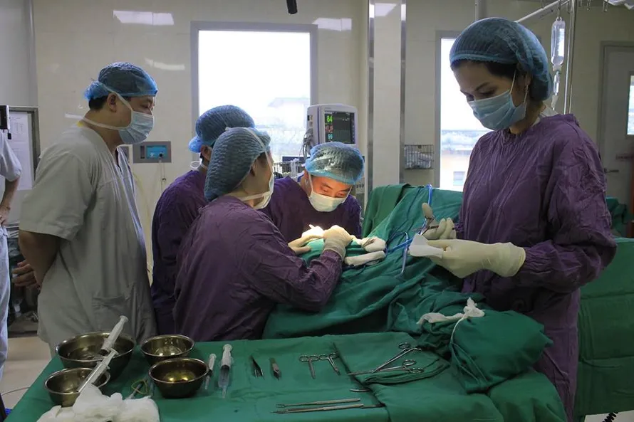 Các BS đang phẫu thuật tạo hình lại vành tai cho bệnh nhân. Ảnh: BV E cung cấp