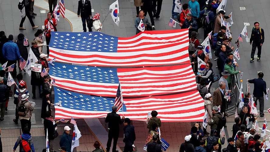 Những người ủng hộ Tổng thống Mỹ Donald Trump cầm cờ Mỹ khi đang chờ đoàn xe của ông Trump chạy qua ở khu vực trung tâm Seoul (Hàn Quốc). Ảnh: Kim Kyung Hoon