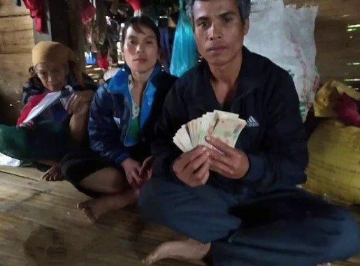 Vợ chồng ông Ăm Diệu và số tiền được phát hiện trong số áo quần cũ mà mạnh thường quân trao tặng